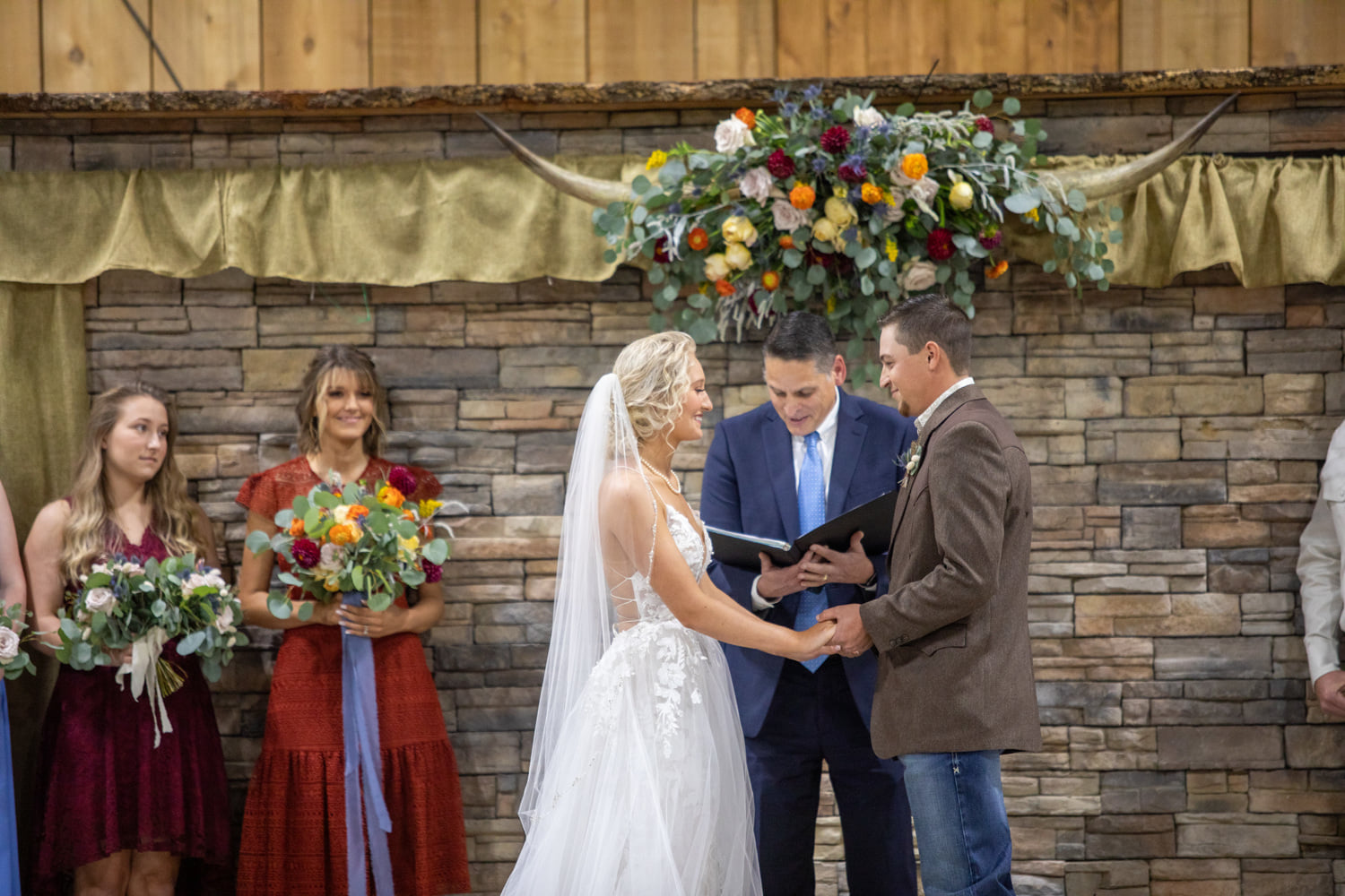 couple saying vows in front of large floral arrangement with steer horns