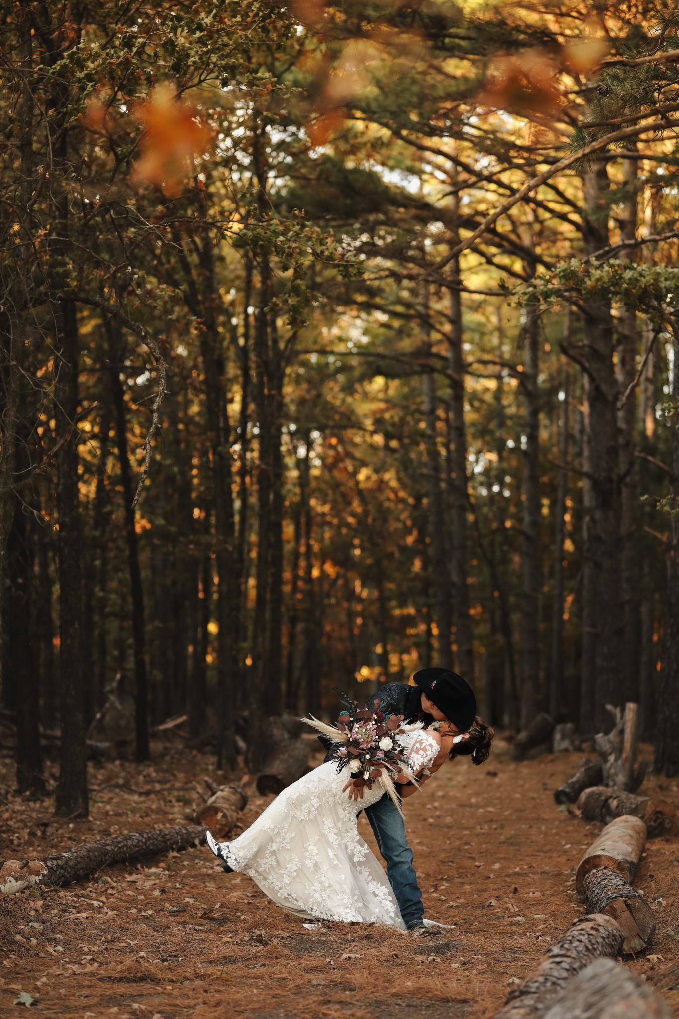 bride and groom kissing surrounded by fall trees