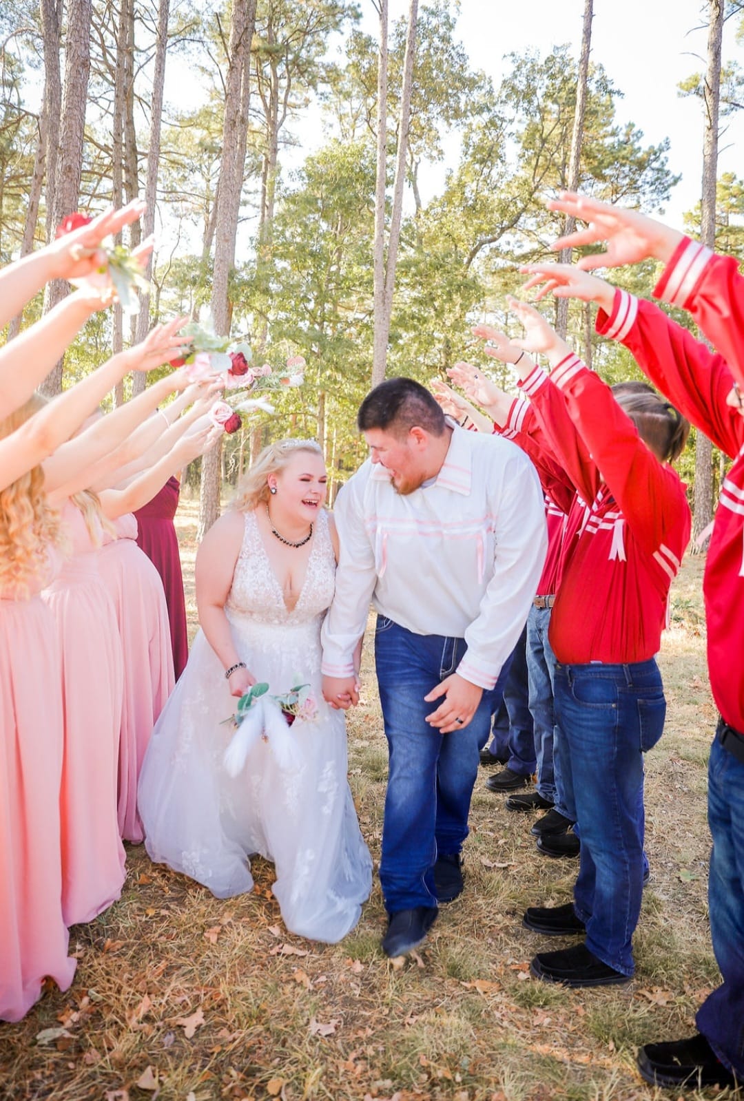 bride and groom walking between wedding party's arms