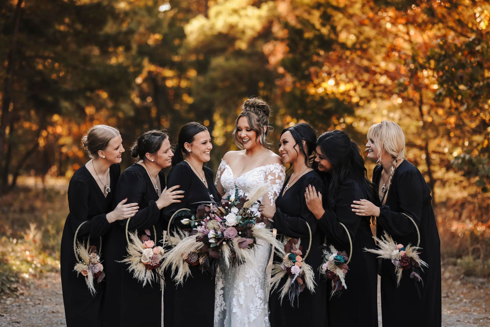 bride with bridesmaids wearing black dresses and hoop bouquets
