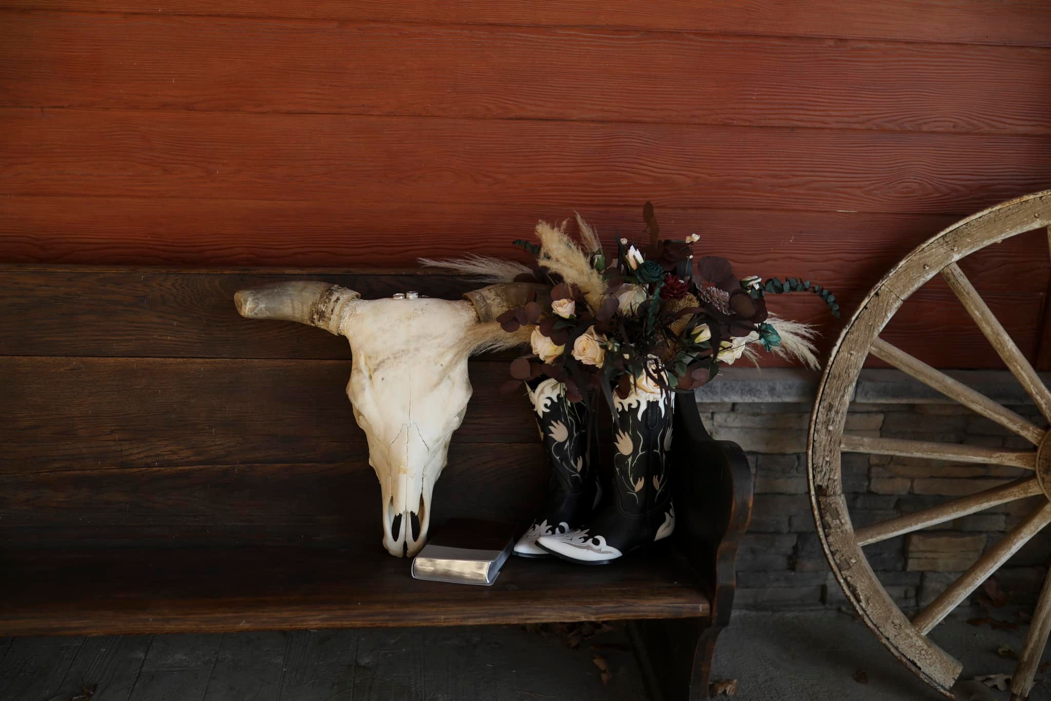 steer skull and bouquet in cowboy boots sitting on antique church pew