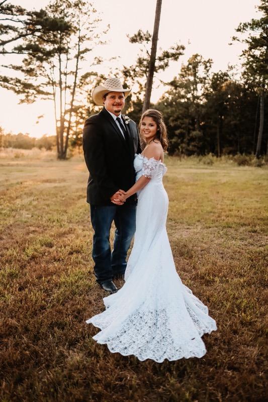 groom in cowboy hat with bride in lace gown