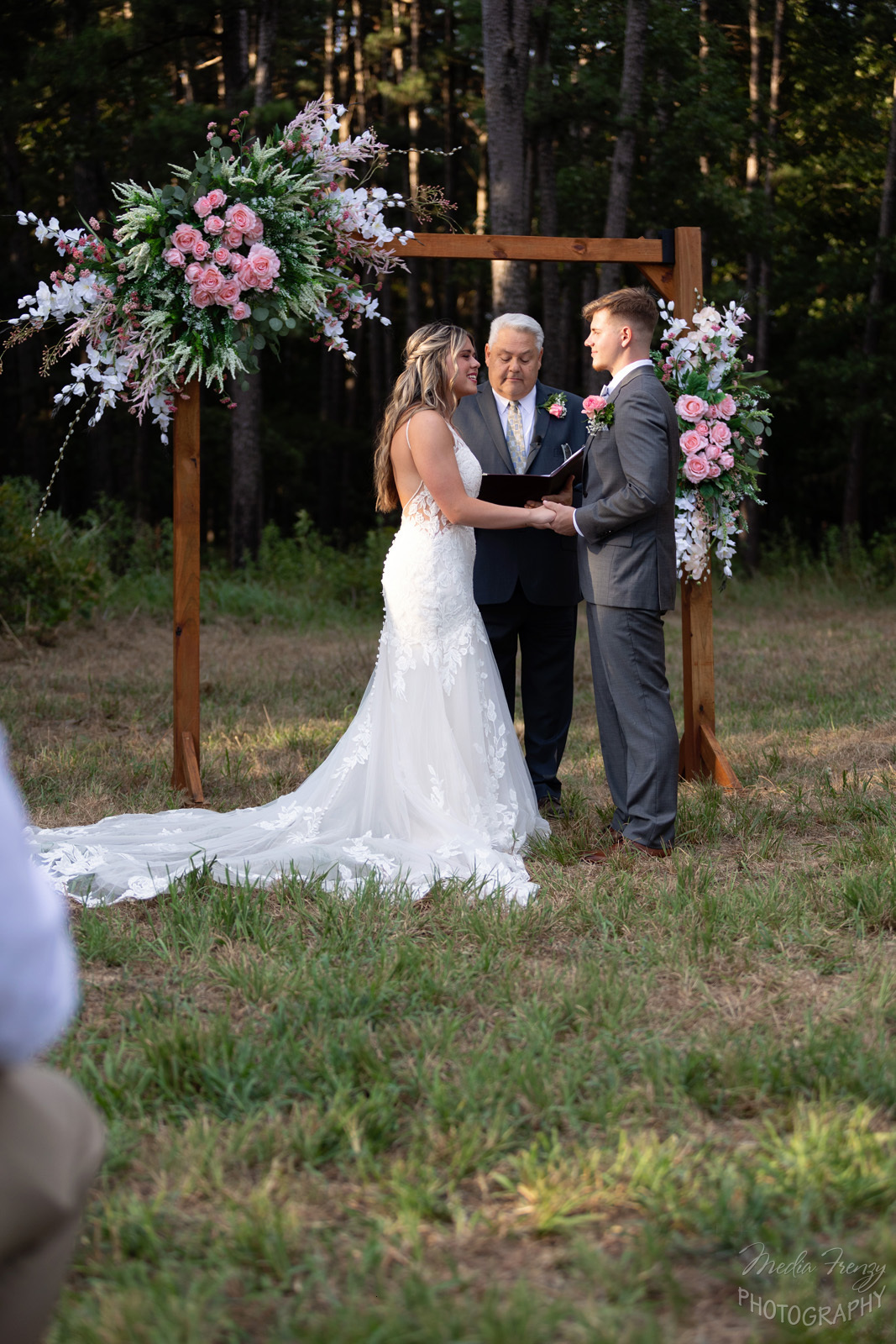 bride and groom saying vows under wooden arch