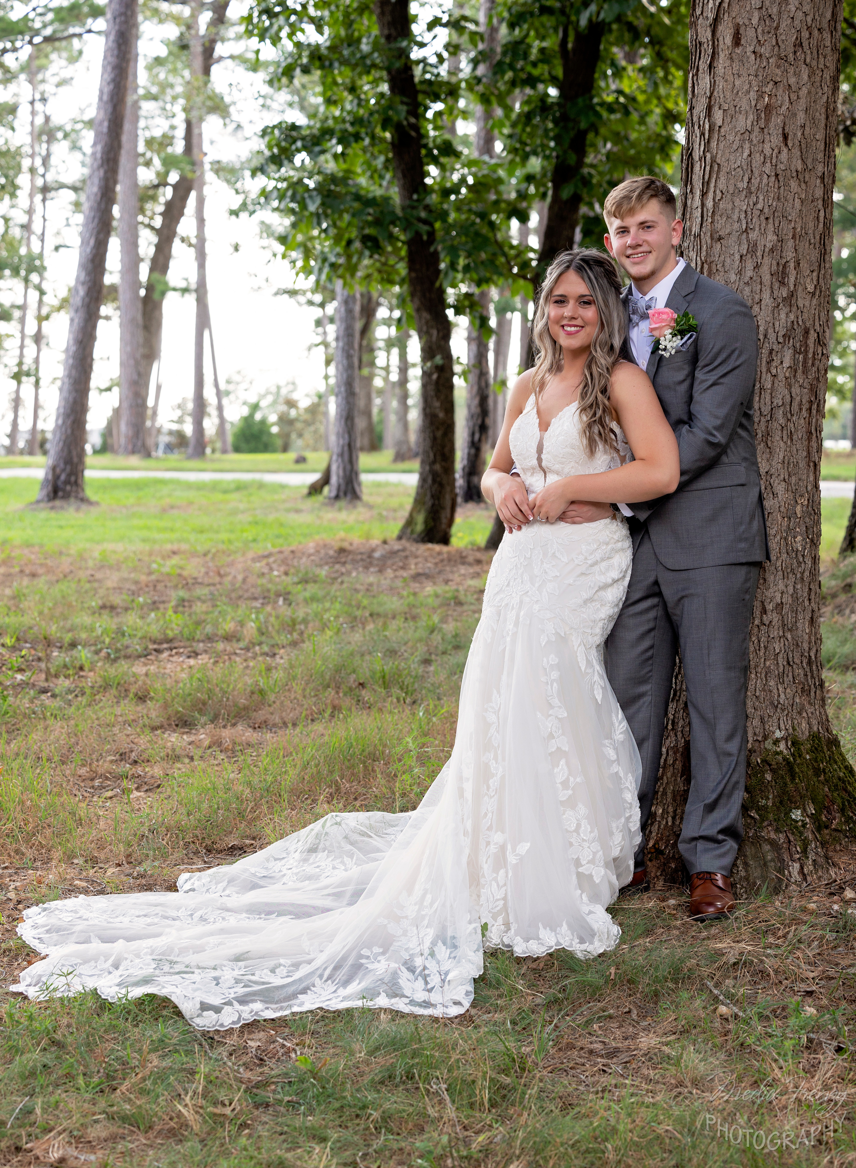groom embracing bride under pine tree
